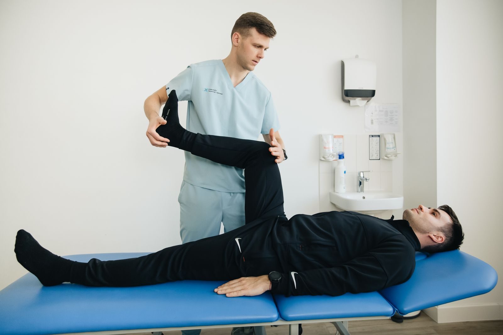 Physiotherapist guiding a patient through a leg stretch on a treatment table