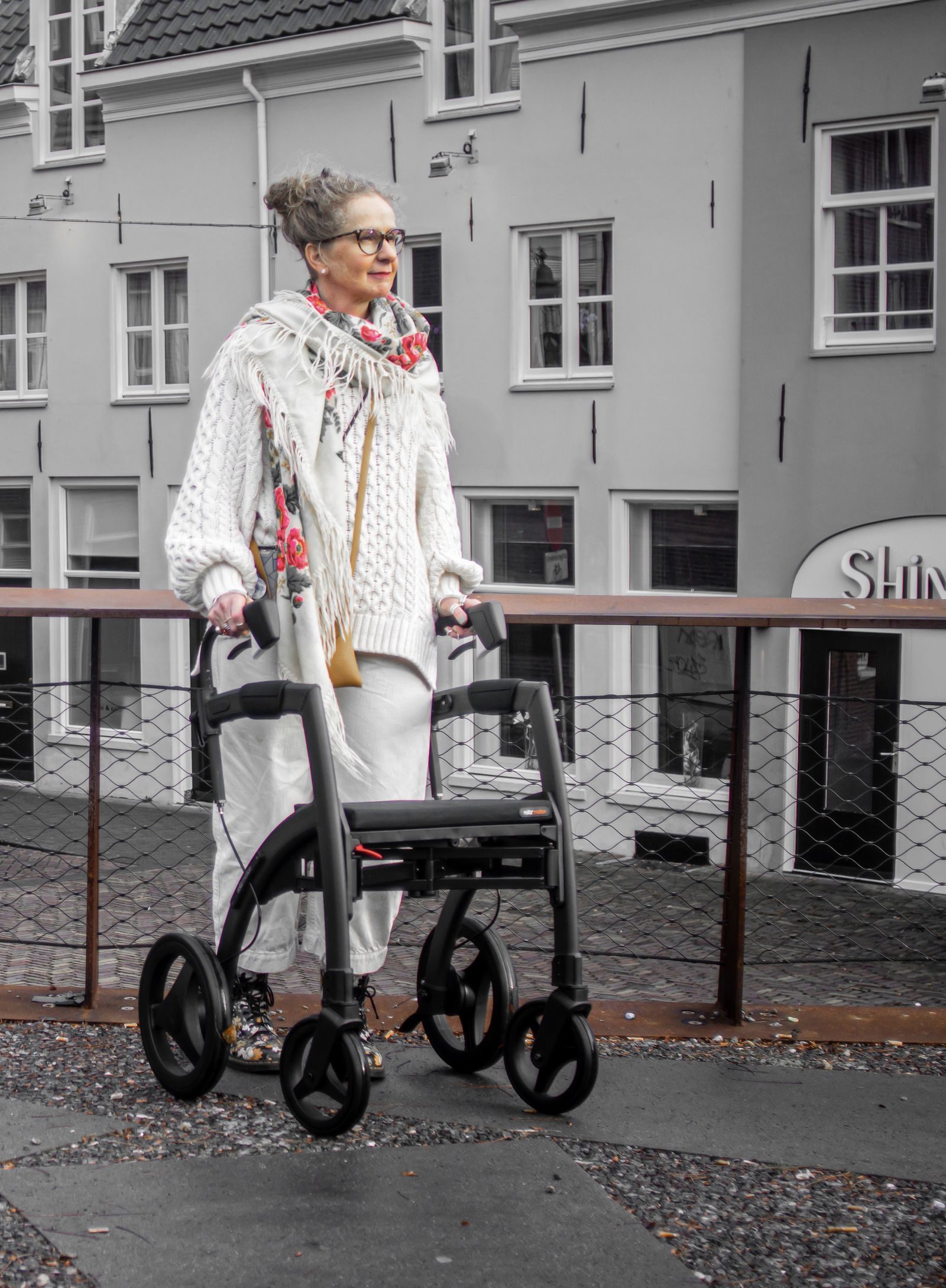 Older woman walking outdoors using a four-wheeled walker for support