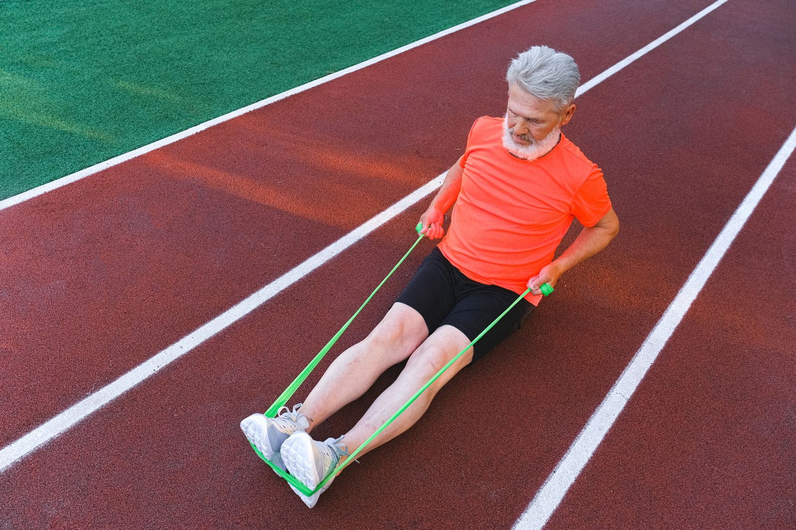 Older runner training with a resistance band on a running track