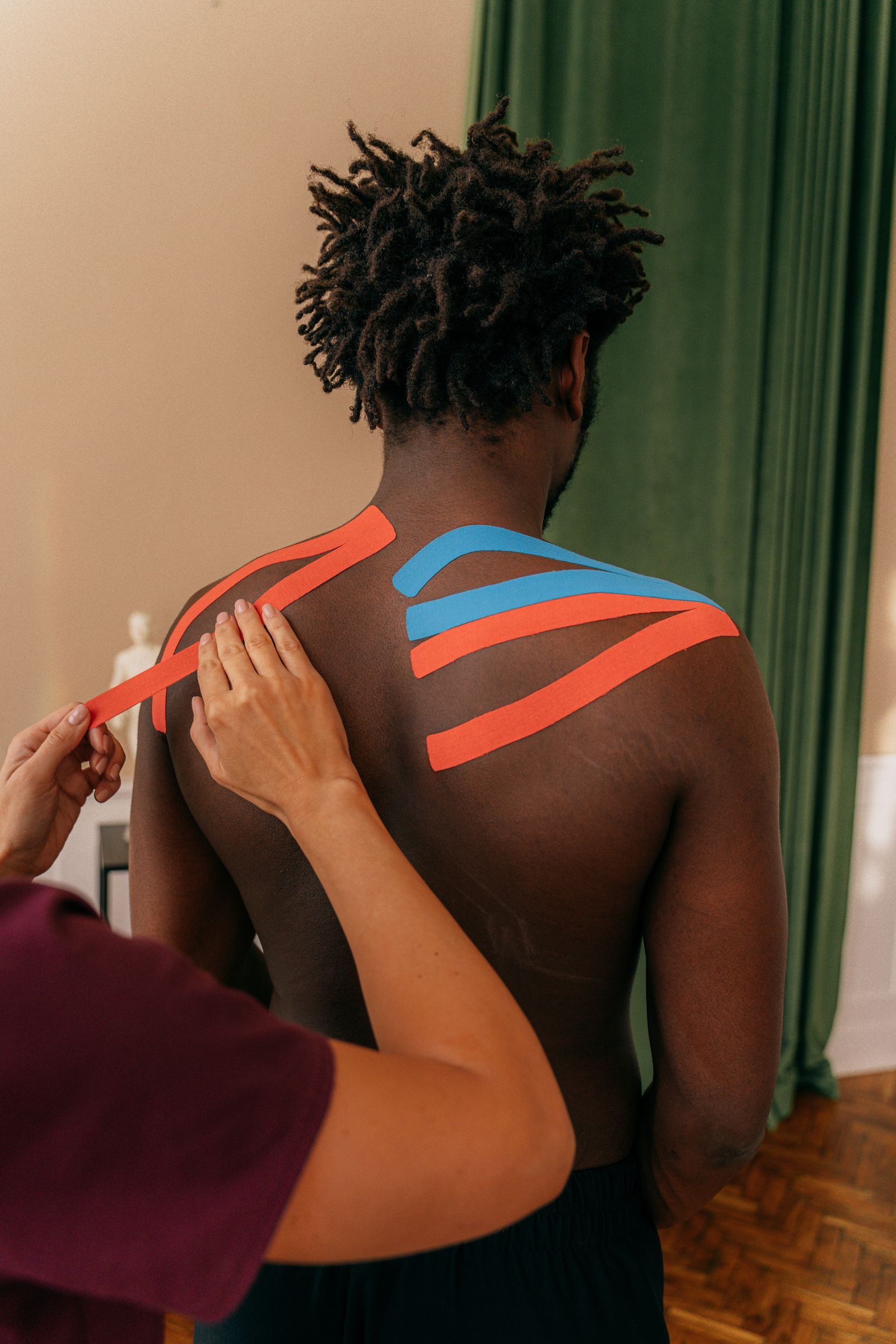 Therapist applying kinesiology tape to an athlete’s shoulder